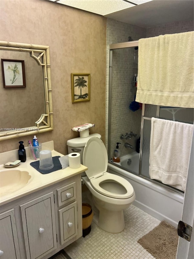 full bathroom with combined bath / shower with glass door, vanity, toilet, and tile patterned flooring