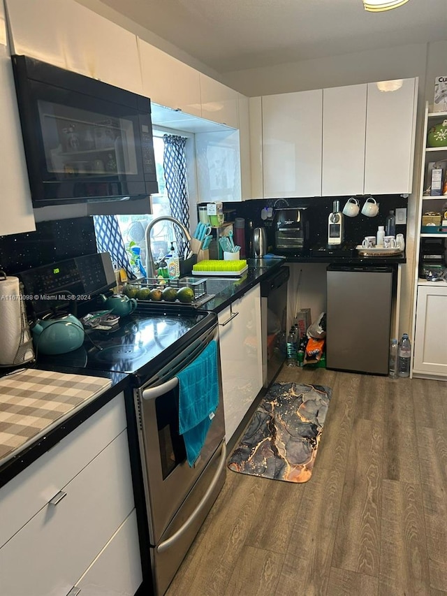 kitchen with white cabinets, sink, tasteful backsplash, stainless steel appliances, and hardwood / wood-style floors