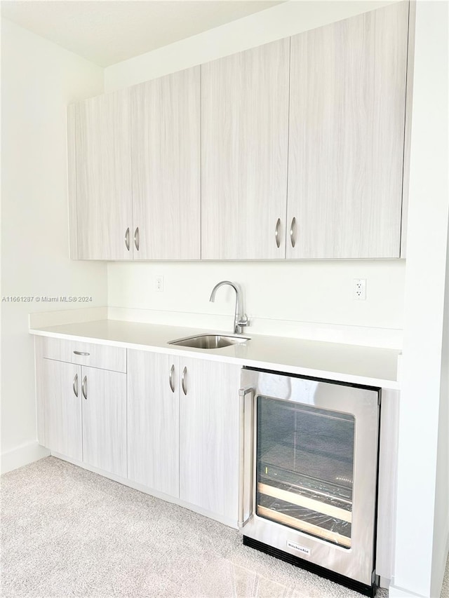 bar featuring light brown cabinetry, wine cooler, and sink