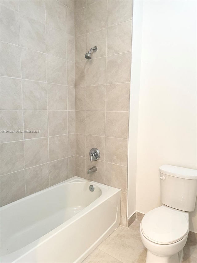 bathroom featuring tile patterned flooring, tiled shower / bath combo, and toilet