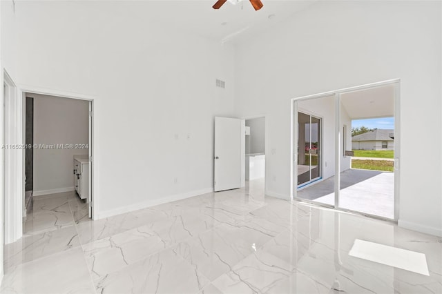 unfurnished bedroom featuring access to outside, a towering ceiling, and ceiling fan