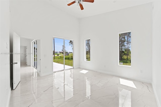 unfurnished room with ceiling fan, plenty of natural light, and a high ceiling