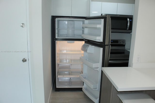 kitchen featuring fridge, black stove, dark hardwood / wood-style flooring, and white cabinetry