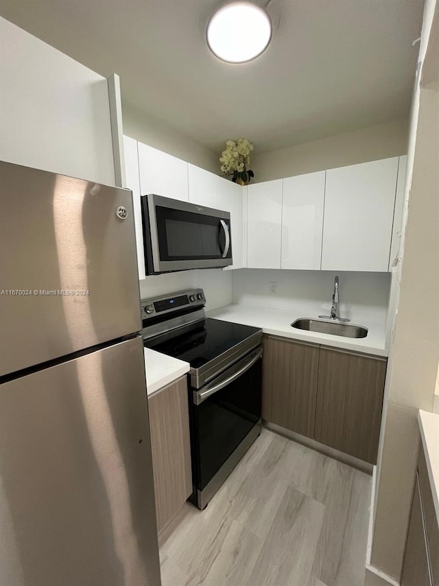 kitchen with stainless steel appliances, sink, and white cabinetry