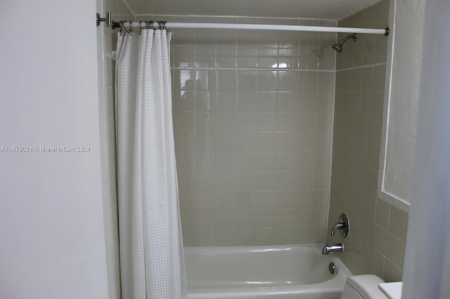 bathroom featuring shower / tub combo and toilet