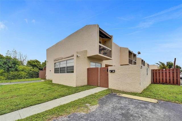 view of side of home featuring a balcony and a yard