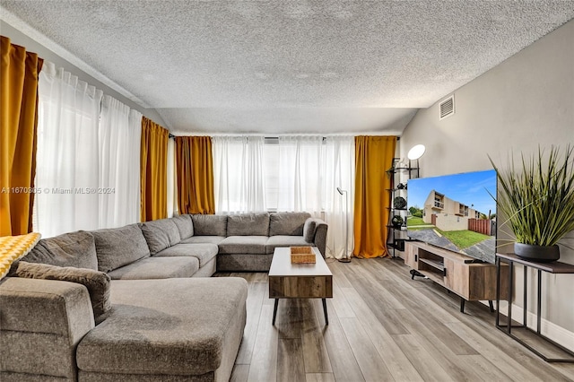 living room with light wood-type flooring, a textured ceiling, and lofted ceiling