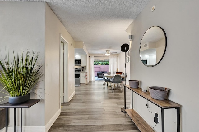 hallway with light hardwood / wood-style flooring and a textured ceiling