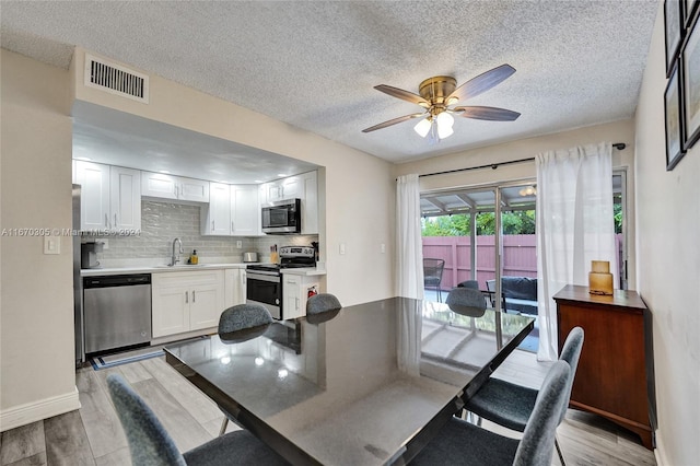 dining room with light wood-type flooring, ceiling fan, a textured ceiling, and sink