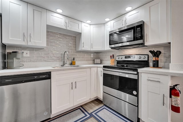 kitchen featuring stainless steel appliances, sink, tasteful backsplash, and white cabinetry