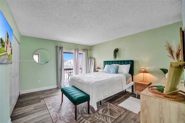 bedroom with a textured ceiling, hardwood / wood-style flooring, and access to outside