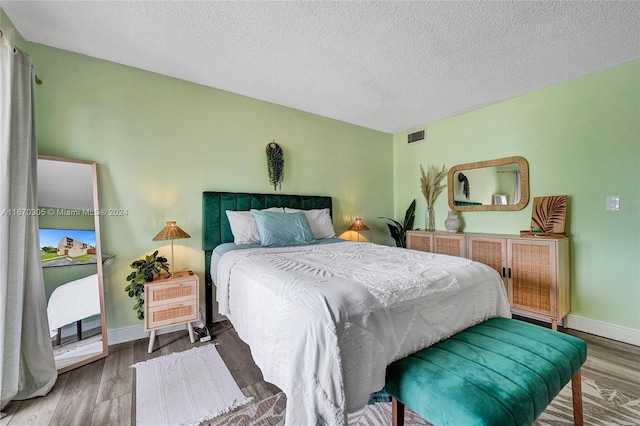 bedroom with a textured ceiling and wood-type flooring