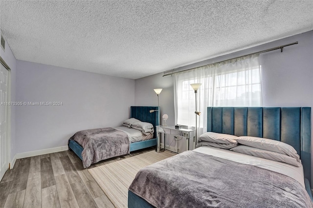 bedroom with light hardwood / wood-style flooring and a textured ceiling