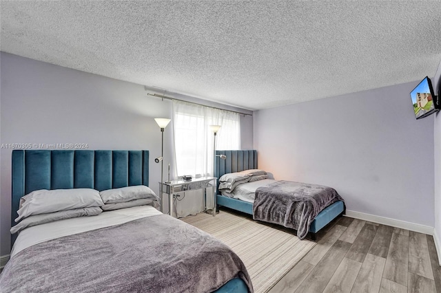 bedroom with a textured ceiling and light hardwood / wood-style floors