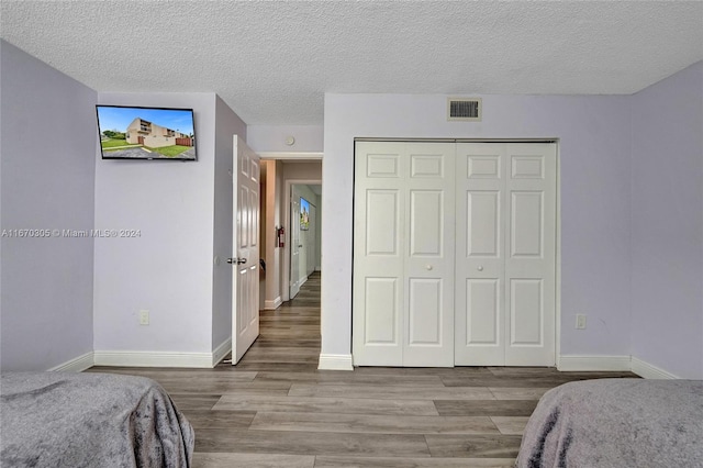 bedroom with light wood-type flooring, a closet, and a textured ceiling