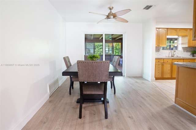 dining space with sink, a healthy amount of sunlight, and light wood-type flooring