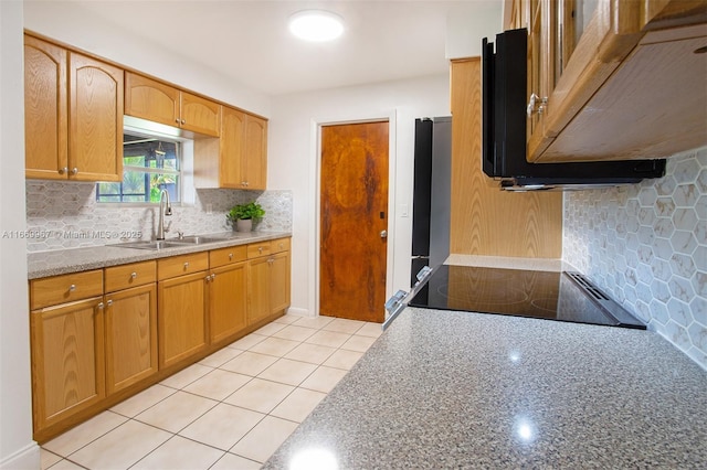 kitchen with sink, tasteful backsplash, light stone counters, light tile patterned floors, and stove