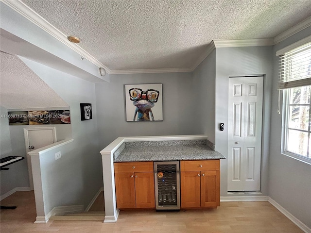 bar with a textured ceiling, light hardwood / wood-style flooring, beverage cooler, and crown molding