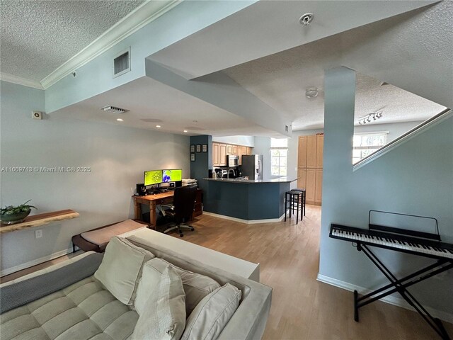 living room with a textured ceiling, light wood-type flooring, and crown molding