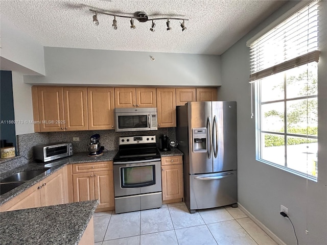 kitchen with tasteful backsplash, a textured ceiling, stainless steel appliances, sink, and light tile patterned floors