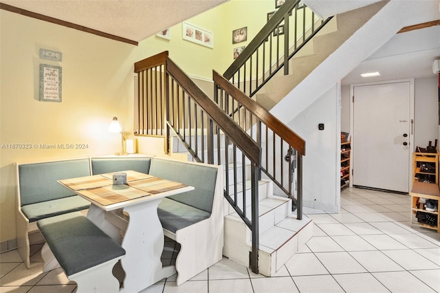 tiled dining space with breakfast area, crown molding, a textured ceiling, and lofted ceiling