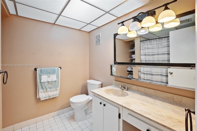 bathroom featuring vanity, a drop ceiling, toilet, and tile patterned flooring