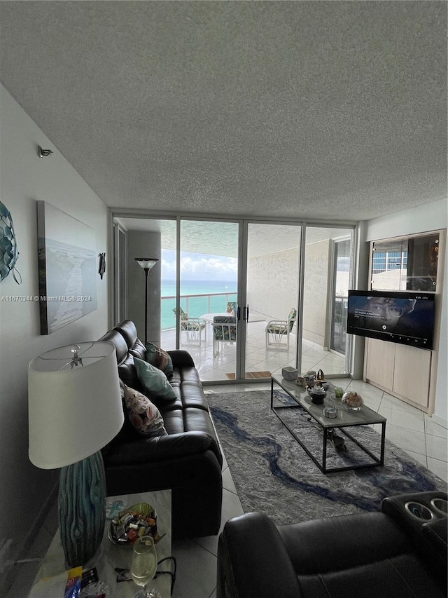 tiled living room featuring a textured ceiling, floor to ceiling windows, and plenty of natural light