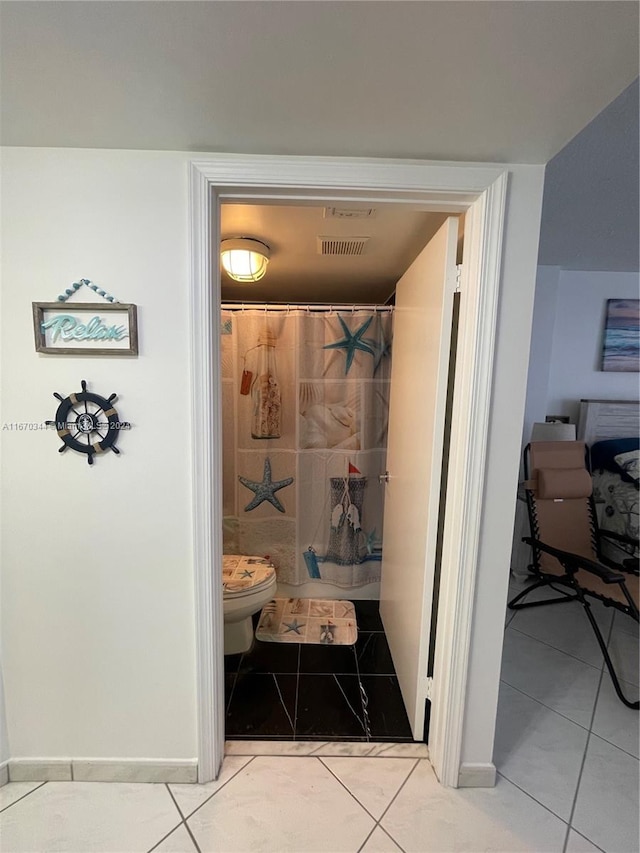 bathroom with toilet, a shower with shower curtain, and tile patterned floors