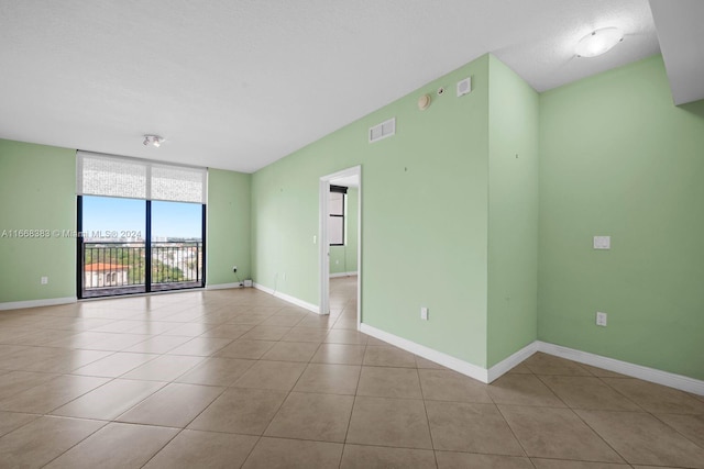 unfurnished room with a textured ceiling and light tile patterned floors