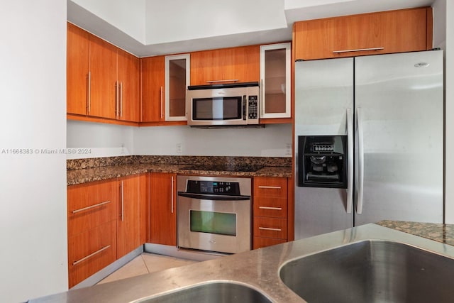 kitchen featuring dark stone counters, appliances with stainless steel finishes, and light tile patterned flooring