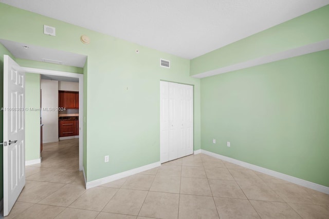 unfurnished bedroom with light tile patterned flooring and a closet