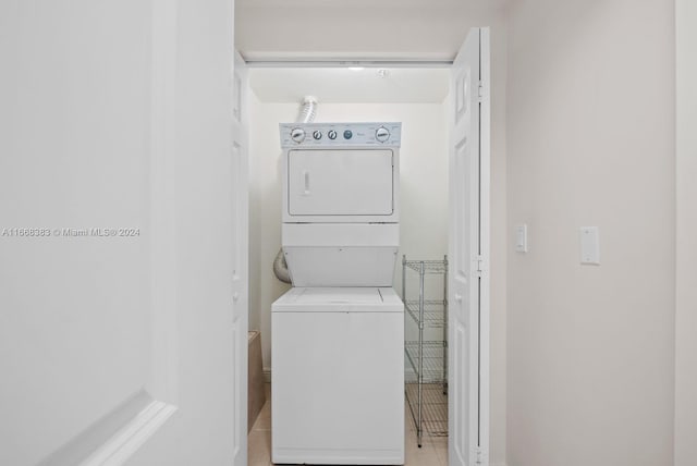 laundry area featuring light tile patterned floors and stacked washing maching and dryer