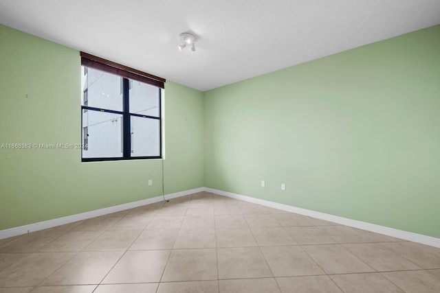 tiled empty room featuring a textured ceiling