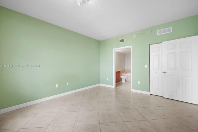 unfurnished bedroom featuring light tile patterned floors and ensuite bathroom