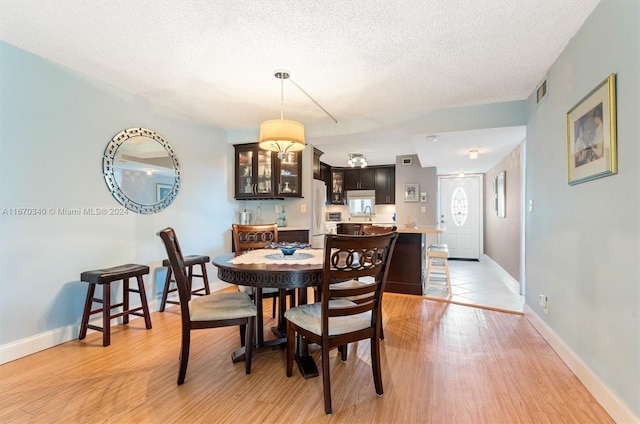 dining space with light hardwood / wood-style flooring, a textured ceiling, and sink