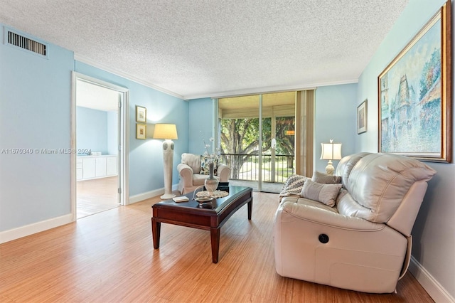 living room featuring ornamental molding, light hardwood / wood-style floors, and a textured ceiling