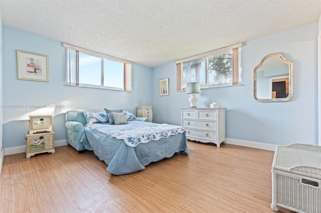 bedroom with multiple windows, a textured ceiling, and light hardwood / wood-style flooring