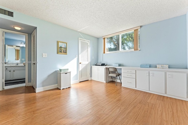 unfurnished office featuring a textured ceiling, light wood-type flooring, and sink