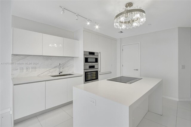 kitchen featuring hanging light fixtures, sink, a kitchen island, white cabinetry, and black electric stovetop