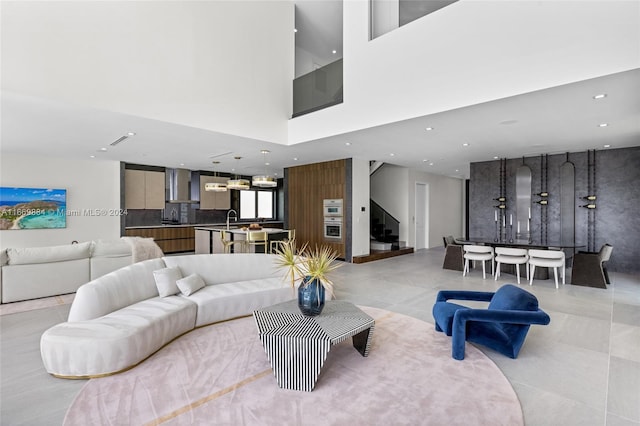 living room featuring a high ceiling, sink, and light tile patterned floors