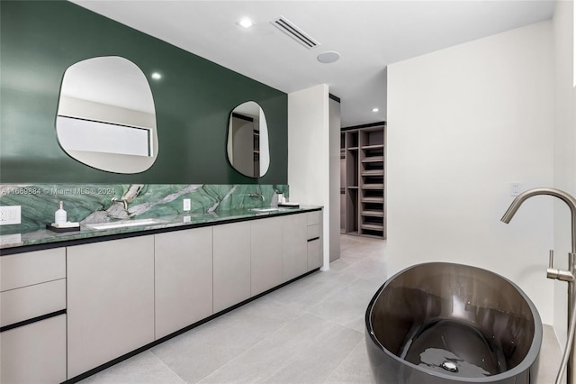 bathroom with decorative backsplash, a tub to relax in, vanity, and tile patterned floors