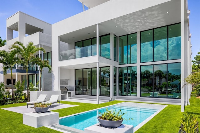 rear view of property featuring a balcony and a yard