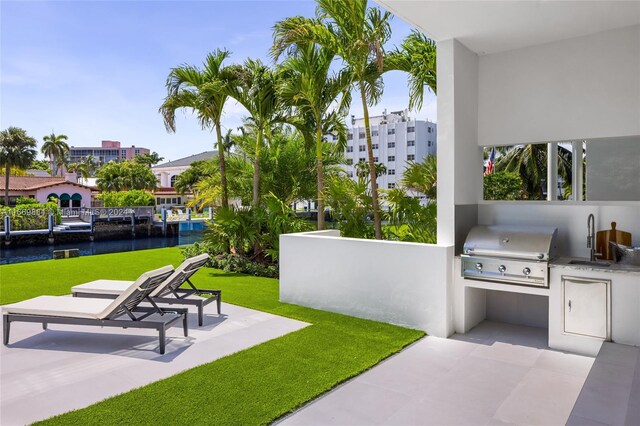 view of patio with area for grilling, sink, and a water view