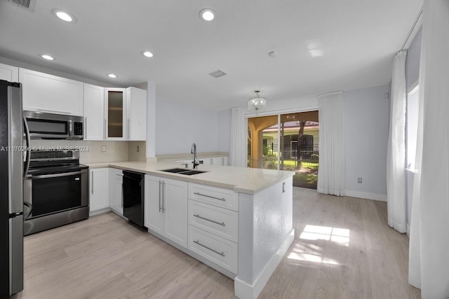 kitchen with sink, appliances with stainless steel finishes, kitchen peninsula, and white cabinetry