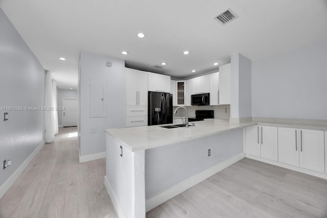 kitchen featuring light hardwood / wood-style floors, sink, white cabinetry, kitchen peninsula, and black appliances