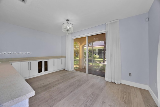 unfurnished room with a chandelier and light hardwood / wood-style floors