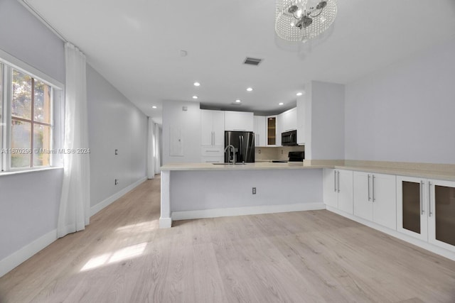 kitchen with white cabinets, black appliances, kitchen peninsula, and light hardwood / wood-style floors