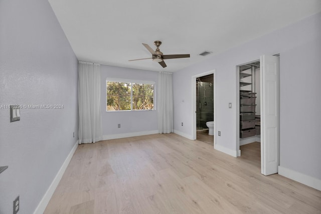 unfurnished bedroom with ceiling fan, light hardwood / wood-style flooring, ensuite bath, and a spacious closet