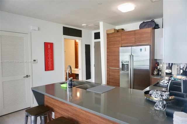 kitchen with stainless steel refrigerator with ice dispenser, kitchen peninsula, a kitchen bar, and sink