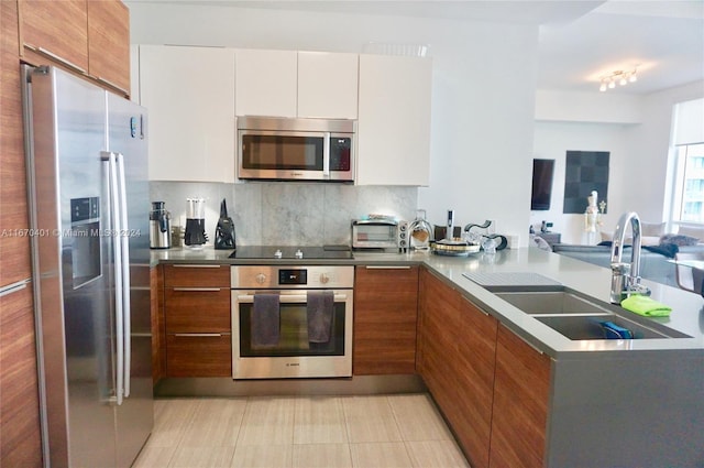 kitchen with white cabinets, light tile patterned flooring, sink, stainless steel appliances, and decorative backsplash